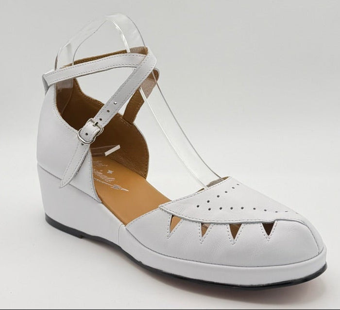 A white vintage wedge sandal with cutout details and an ankle strap.
