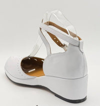 A white vintage wedge heel sandal with ankle straps.